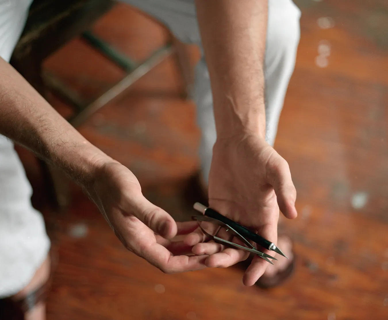 Portrait of visual artist Julien Gardair close up on his hands holding cutting tools