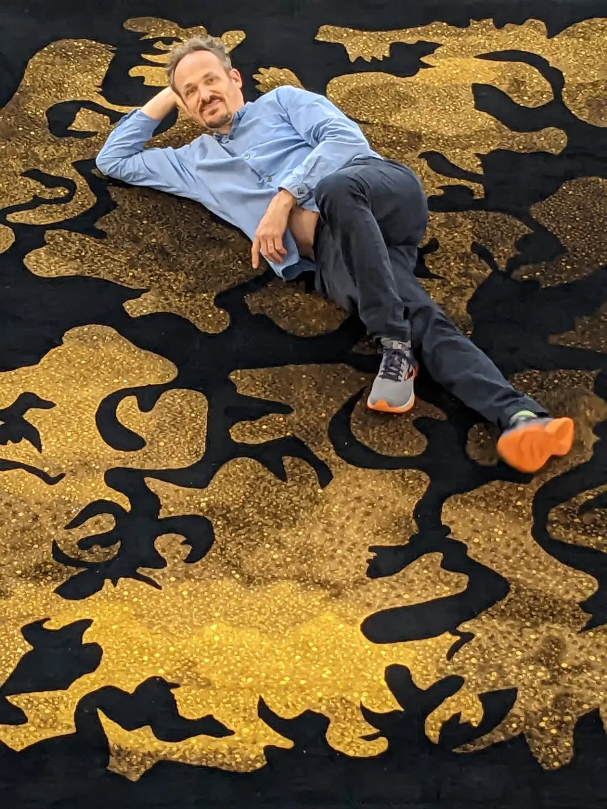 Artist Julien Gardair laying on the Savonnerie carpet he designed Les Javels from the Mobilier National collection