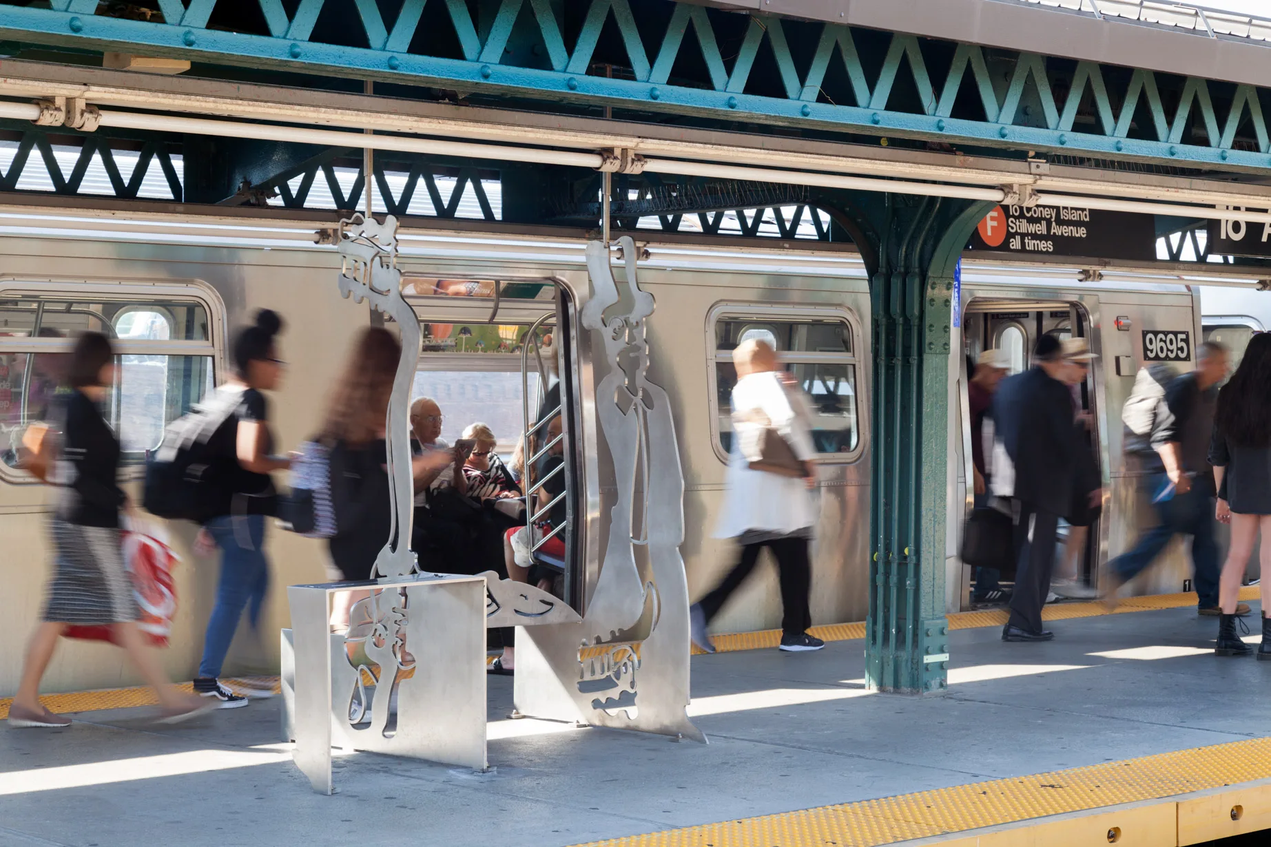 Sculptural bench and windscreen made of a single plate of stainless steel cut along a single line and folded presenting two figures inspired by contemporary and historical figures, in an elevated subway platform in New YOrk