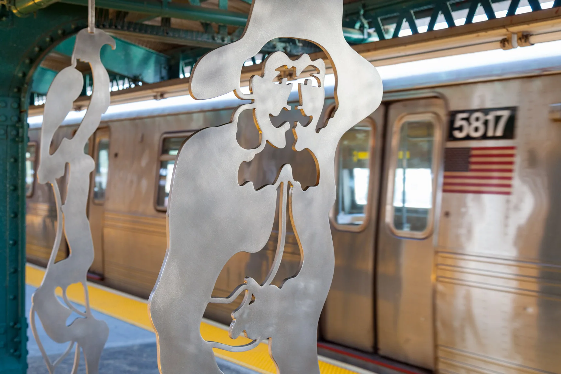 Sculptural bench and windscreen made of a single plate of stainless steel cut along a single line and folded presenting two figures inspired by contemporary and historical figures, in an elevated subway platform in New YOrk